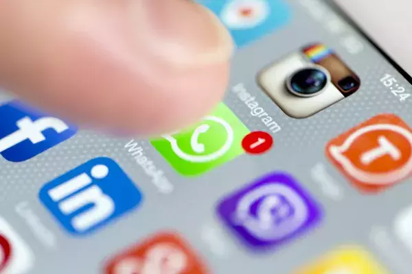 A finger hovering over a whatsapp icon on a mobile phone