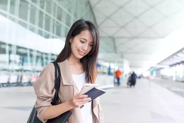 happy passenger looking at mobile phone in airport