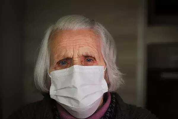 Senior woman wearing a face mask and looking scared