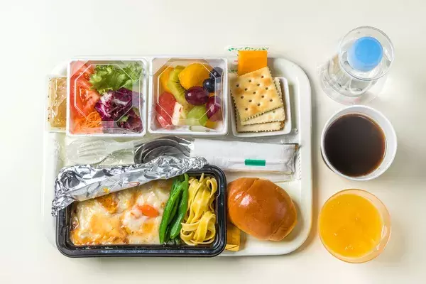 An airline meal served on a plastic tray with plastic cutlery and plastic water bottles and cups