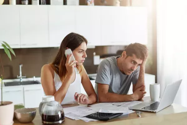 A stressed couple on the phone and at the laptop 