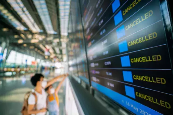 Passengers looking at a board of cancelled flights in an airport